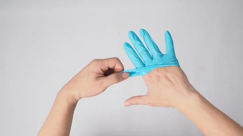 Left hand is pulling right hand with blue latex gloves on white background. Stock Photos