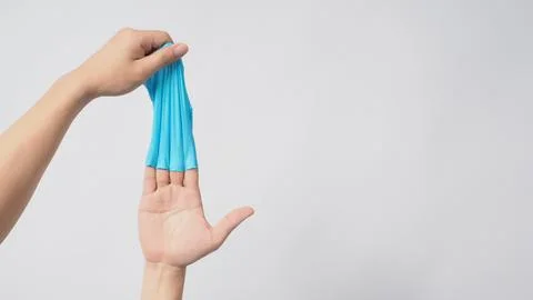 Left hand is pulling right hand with blue latex gloves on white background. Stock Photos