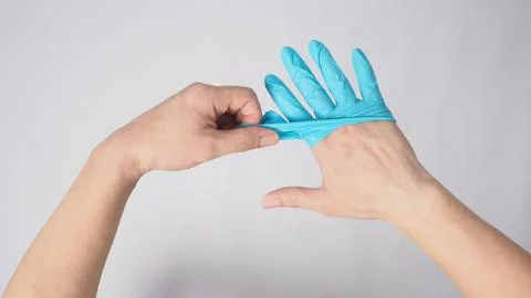 Left hand is pulling right hand with blue latex gloves on white background. Stock Photos