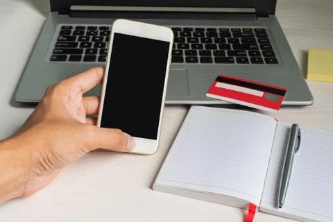 Left hand using smartphone on blackground with laptop, dollars, camera, and c Stock Photos