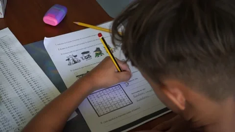 Left handed boy is doing his homework. Kid writes with his left hand Video stock 220056461
