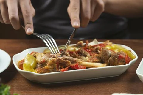 Left-handed man eats lamb stew on the bone with vegetables.Khashlama is popul Stock Photos