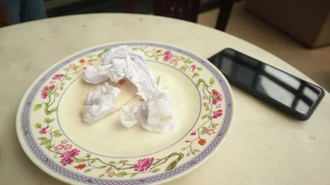 Left over plate filled with used Tissue Paper on Table beside black color mobile Stock Footage 154754683