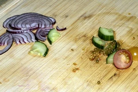 Left over salad from dinner chopped cucumber tomato onion food waste on cho.. Stock Photos