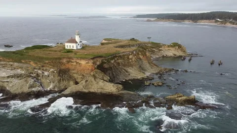 Left Pan Aerial View of Cape Arago Lighthouse with Waves Crashing on Rocks Stock Footage 226011813