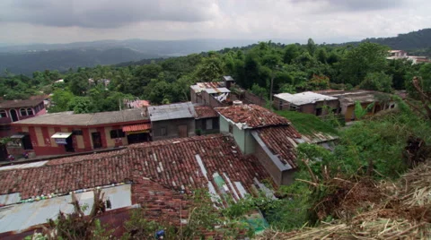 Left pan over roofs of buildings clustered on a wooded slope in El Salvador Stock Footage 59530697