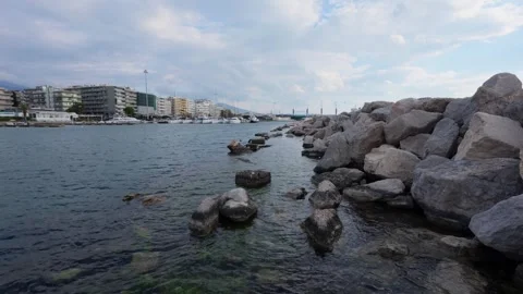 Left pan wide angle over rocky breakwater and coastal city marina Stock Footage 337048740