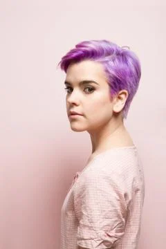 Left profile of a violet-short-haired woman in pink pastel, looking at camera Stock Photos