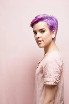 Left profile of a violet-short-haired woman in pink pastel, smiling Stock Photos