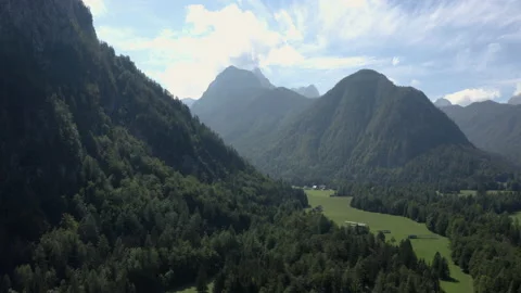 Left to right Aerial flight over a mountain valley with meadows and forests. Video stock 217374546
