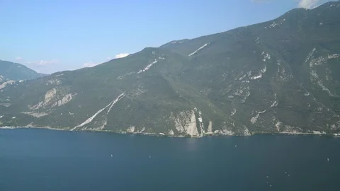Left to right pan real time wide shot of lake Garda and mountains. Lake Garda is Видео 122287671
