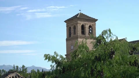 Left-right panning shot of a stone church bell tower with greenery. Видео 55727140