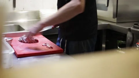 Left side view of a chef cleaning and cutting meat Stock Footage 137945766