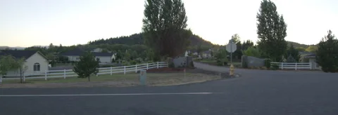 Left Side view of a Driving Plate: Car travels at dusk through an affluent rural Stock Footage 59329455