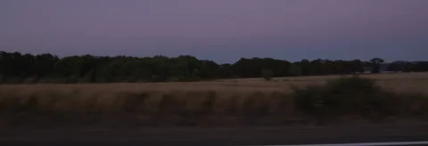 Left Side view of a Driving Plate: Car travels at dusk past farms and fields on Stock Footage 59330283