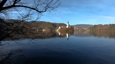 Left truck moving behind tree silhouette with lake Bled island in background Stock Footage 123168732