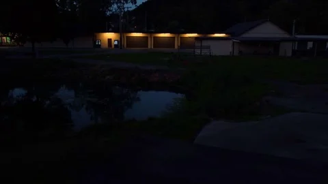 Left to upward pan of park at nighttime with pond reflection Stock Footage 247428206