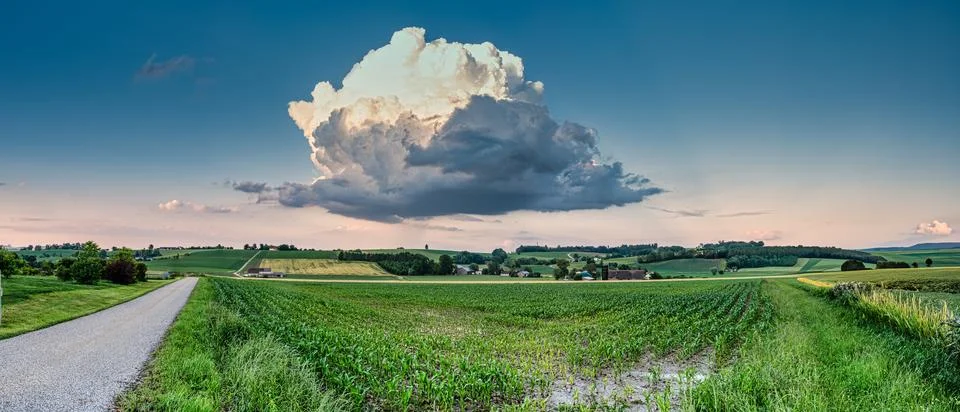 Leftover Storm Cloud Hovering Over Expansive Green Field Foto stock