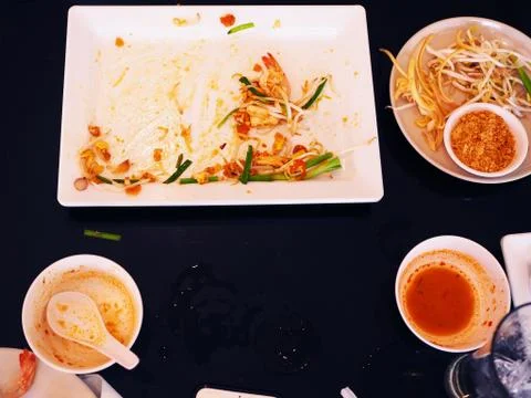 Leftover Thai meal on white ceramic plates, black table 库存照片