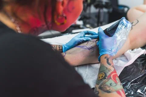 Leg with a pattern and black paint. New tattoo on leg. Tattooing master working Fotos de archivo