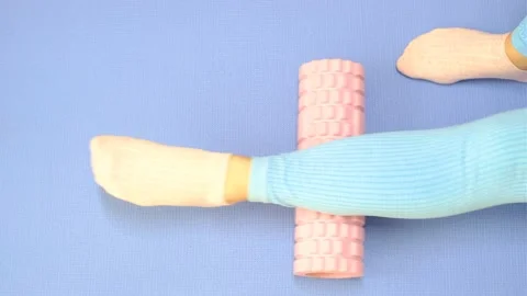 Leg rolls a massage foam roller close-up on blue background, top view. Stock Footage 211991380