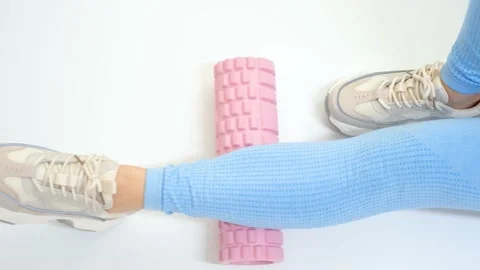 Leg rolls a massage foam roller close-up on white background, top view. Stock Footage 219459783