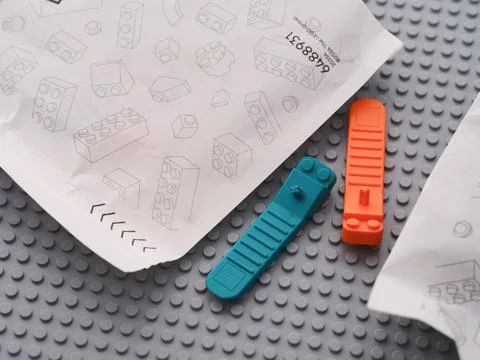 Lego brick separators lying between paper bags with Lego pieces Foto stock