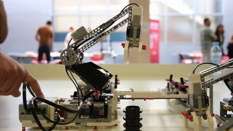 Lego crane robot pick item and move it  with people in background Stock Footage 113138098
