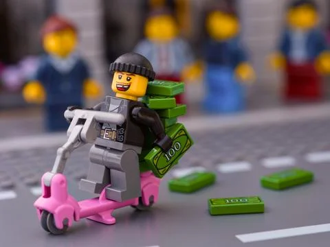 Lego robber riding scooter with a stack of money on it and dropping money Stock Photos