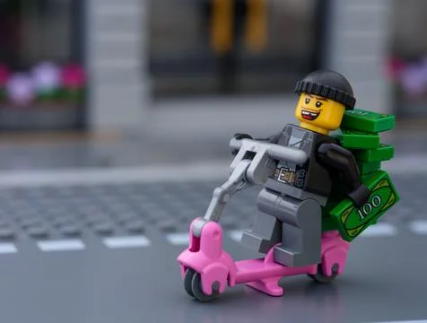 Lego robber riding scooter with a stack of money on it Stock Photos