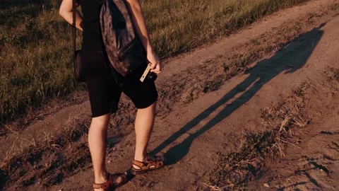 The legs and shadow of a young man dressed in black shorts who has a rug on his Stock Footage 135826356