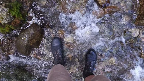 Legs in ankle boots standing in shallow mountain creek, view from above Vídeos de archivo 303553729