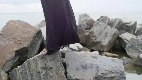 Legs of a beautiful girl standing on rocks on the beach Stock Footage