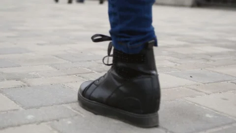 Legs in black boots walk down the sidewalk Stock Footage 103055592