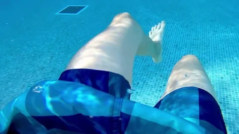 Legs of a boy jumping and playing in a swimming pool, underwater footage Stock Footage 75638115