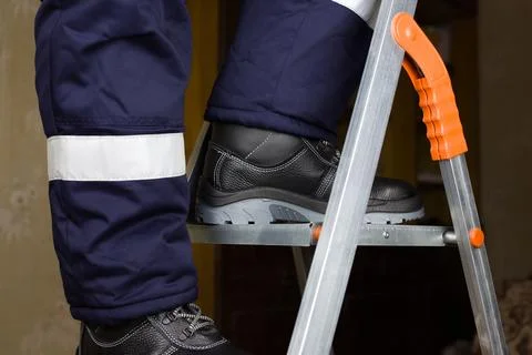 Legs of builder on metal stepladder Stock Photos
