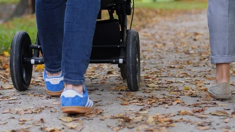 Legs camera parents walk roll a stroller with baby child on a city park alley Stock Footage 117829817