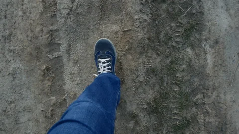 Legs in dark sneakers and white lace-up walk on the ground. view from above Stock Footage 105481453