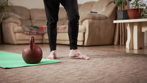 The legs of elderly man with an athletic build doing warm-up exercises in a room Video stock 333245897