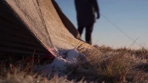 The legs of an explorer walking around a cold frosty wild camping tent Vídeo Stock 255025116