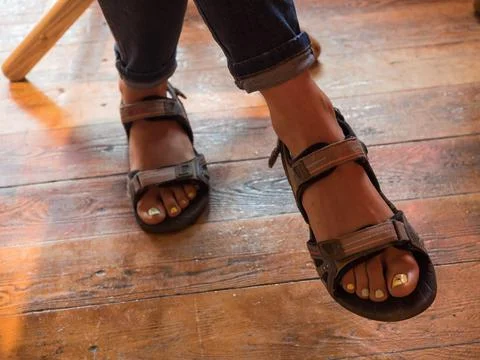 Legs in flip flops under the table on the background of the floor Stock Photos