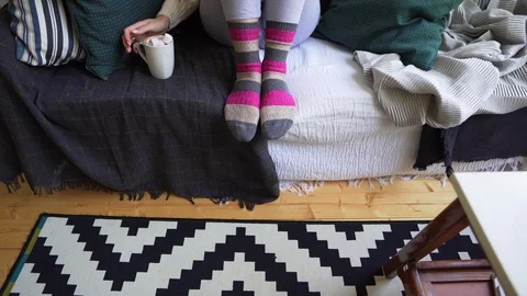Legs of a girl on a sofa in warm multi-colored socks on a cold winter day in a Stock Footage 114416334