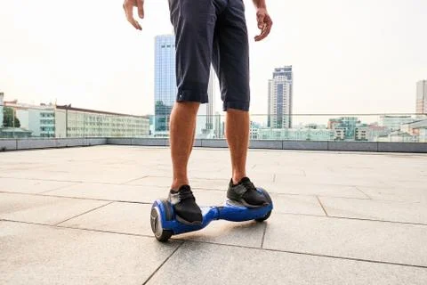 Legs on hoverboard, city background. Stock Photos