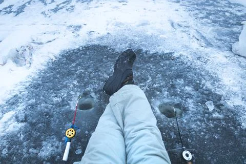 Legs on ice in winter boots and warm pants, winter fishing, ice hole, winter  Foto stock