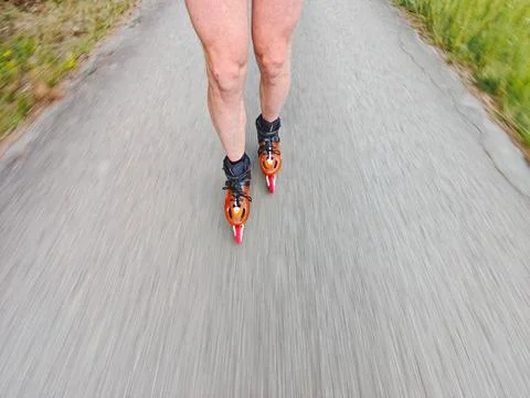 Legs in inline skates boots are moving on asphalt road Stock Photos
