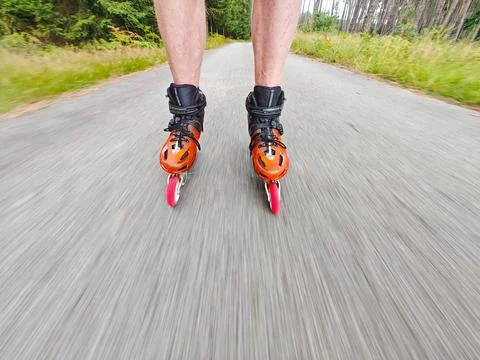 Legs in inline skates boots are moving on asphalt road Stock Photos