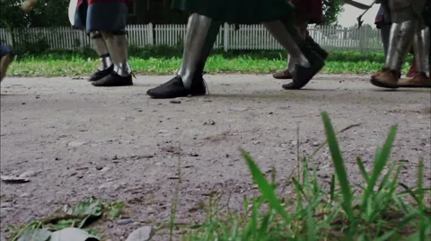 Legs knights in armor marching on the road against a white fence Stock Footage 56472387
