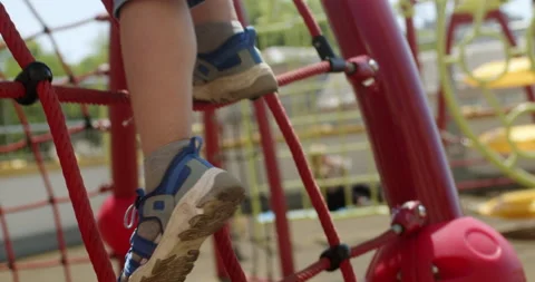 Legs of little boy climbing down rope net on playground Stockbeeldmateriaal 201371447
