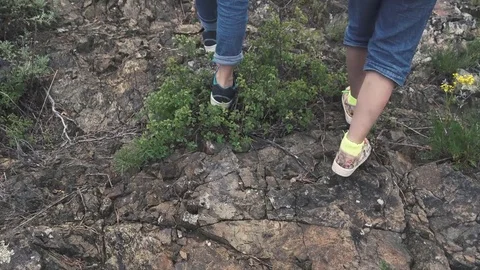 Legs little girls travelers walking on rocky terrain. children are traveling in Stock Footage