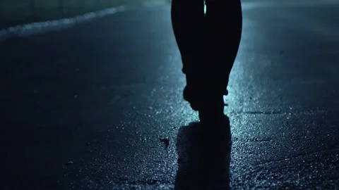 Legs of a man in backlight walking down the street at night. Stockbeeldmateriaal 202353426